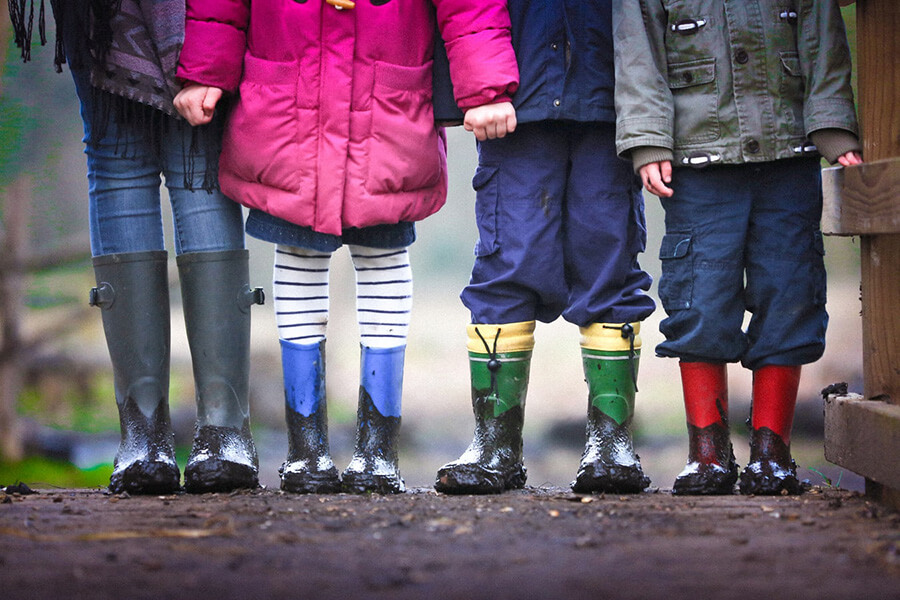 children in rubber boots holding hands