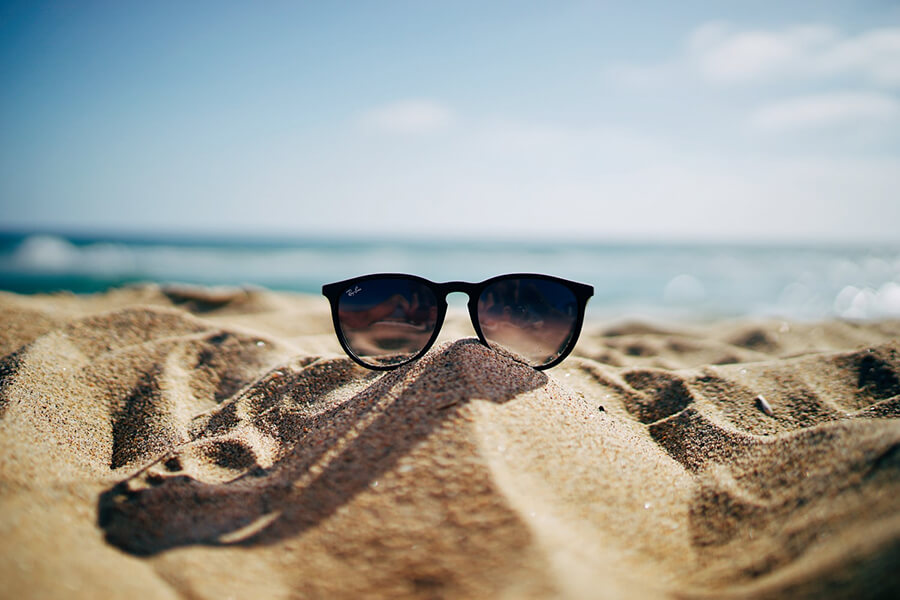 Glasses on sand dune in front of the sea.
